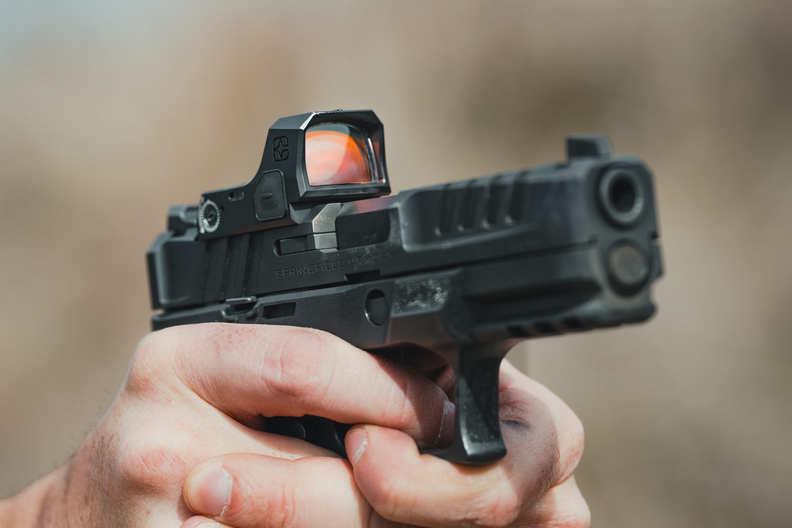 Hands holding a pistol fitted with the Mercury reflex sight